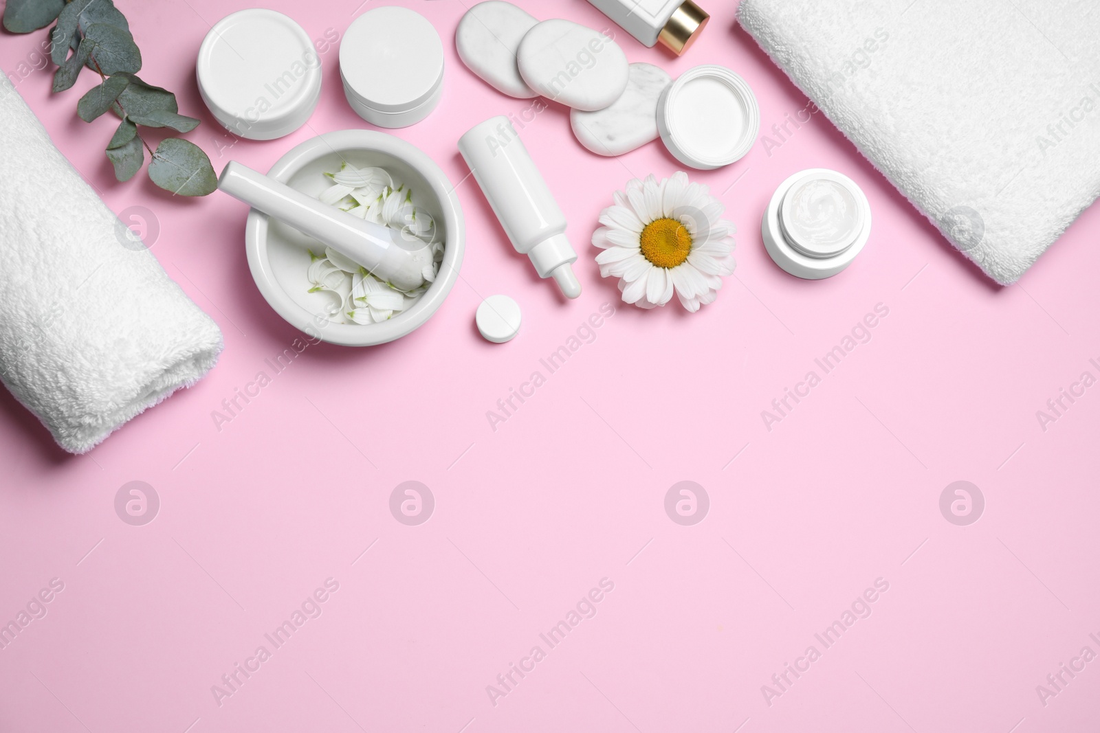 Photo of Flat lay composition with chamomile flower and cream on pink background. Space for text