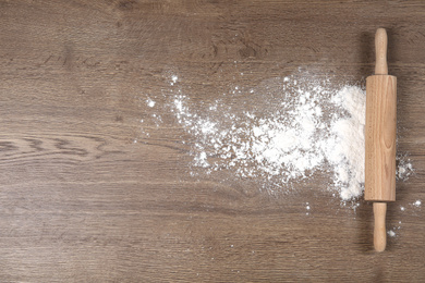 Photo of Flour and rolling pin on wooden table, flat lay