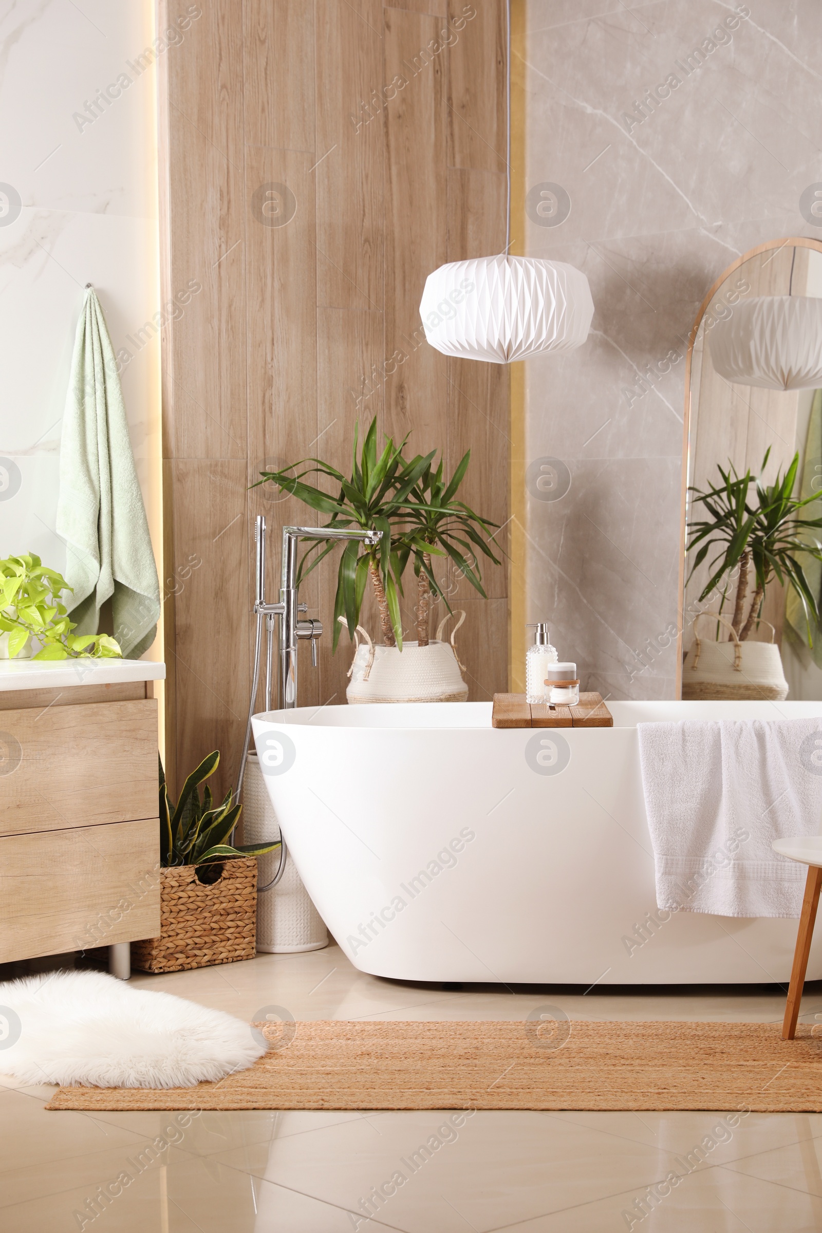 Photo of Modern white tub and beautiful green houseplants in bathroom. Interior design