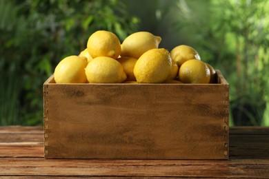 Fresh lemons in crate on wooden table
