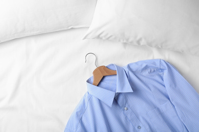 Stylish light blue shirt on bed, space for text. Dry-cleaning service