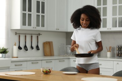 Beautiful woman in stylish underwear and t-shirt serving breakfast indoors, space for text