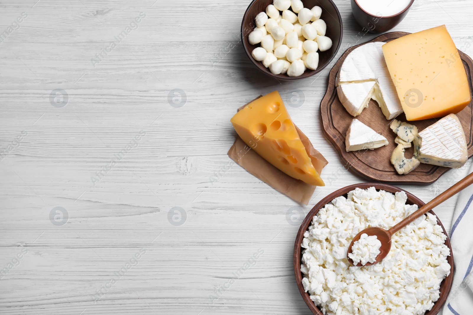 Photo of Clay dishware with fresh dairy products on white wooden table, flat lay. Space for text