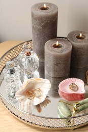 Photo of Perfumes, jewelry and burning candles on wooden makeup table