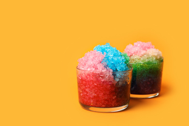 Photo of Rainbow shaving ice in glass dessert bowls on orange background