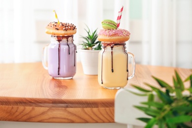 Photo of Mason jars with delicious milk shakes on table