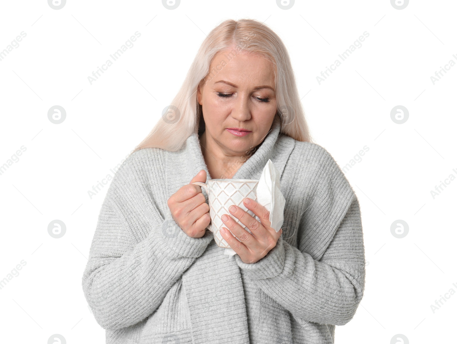 Photo of Mature woman with cup of hot tea suffering from cold on white background