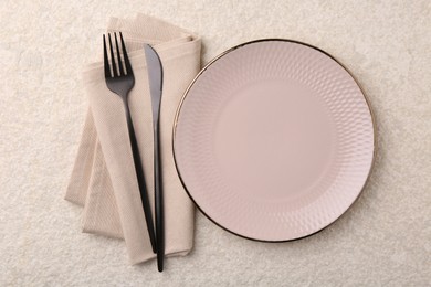 Stylish setting with elegant cutlery on beige textured table, top view