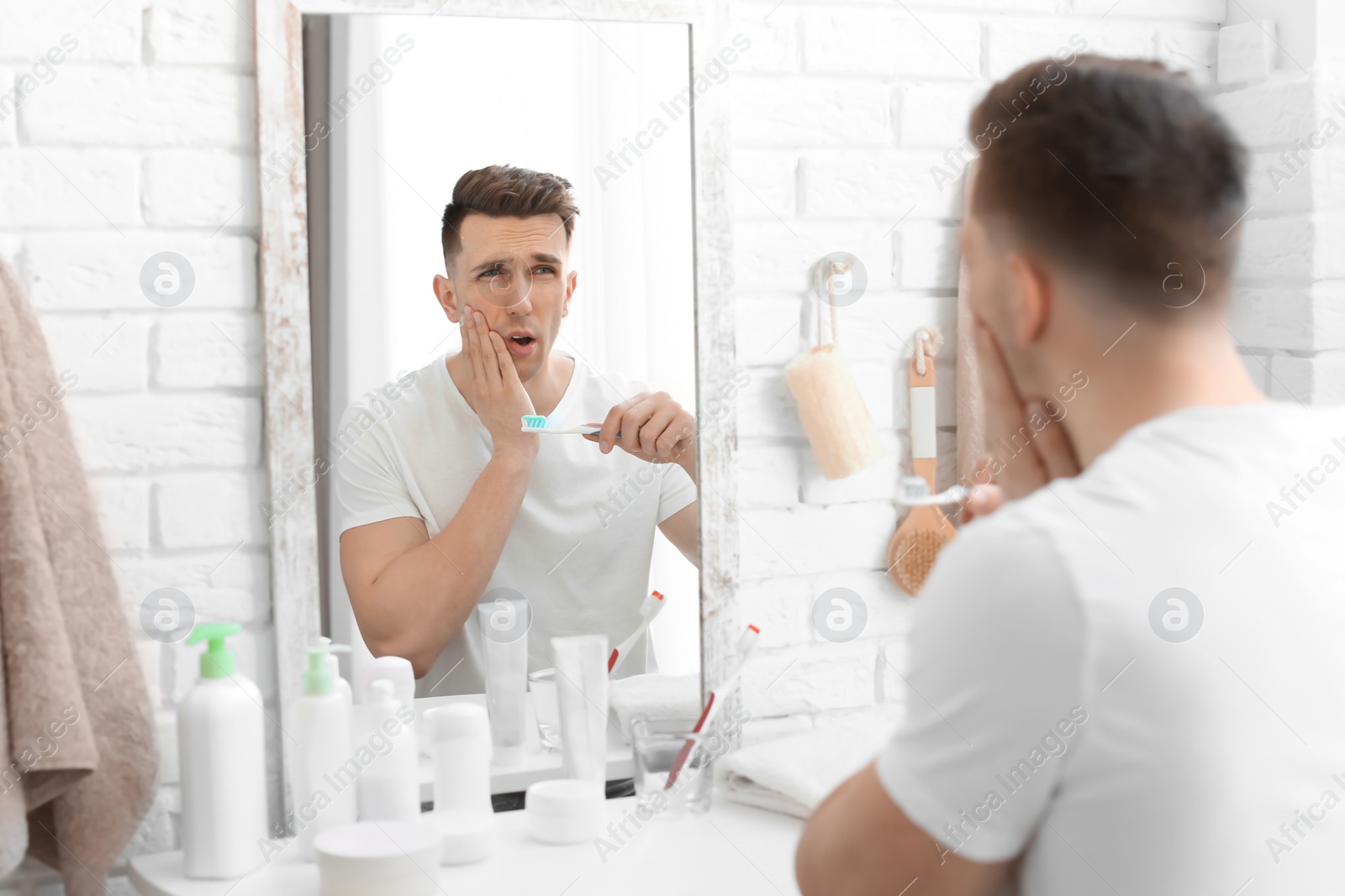 Photo of Young man with sensitive teeth in bathroom