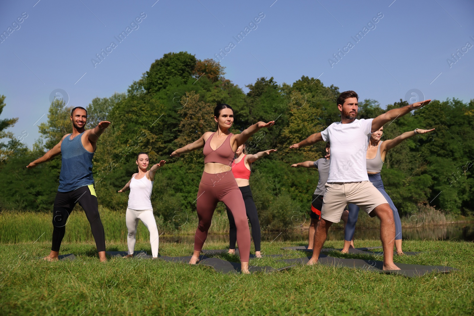 Photo of Group of people practicing yoga on mats outdoors, low angle view