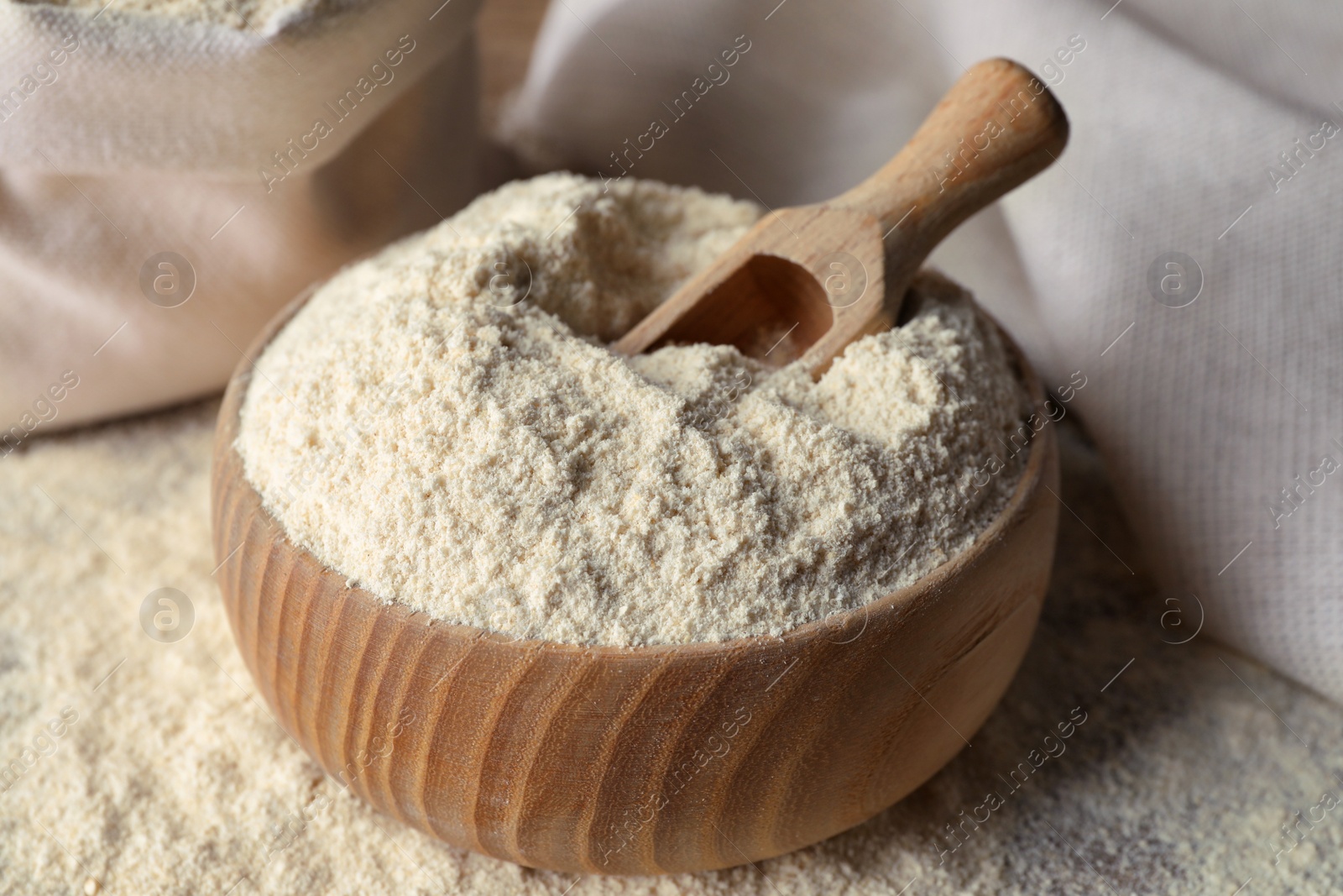 Photo of Wooden bowl with quinoa flour and scoop on table