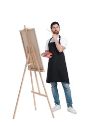 Photo of Artist with brush painting against white background. Using easel to hold canvas