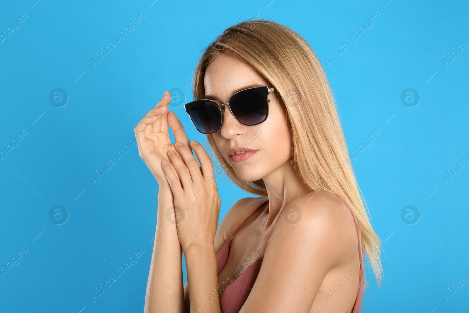 Photo of Beautiful woman in stylish sunglasses on light blue background