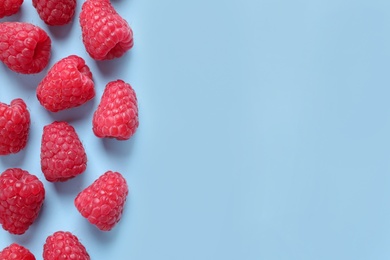 Photo of Fresh sweet ripe raspberries on light blue background, flat lay. Space for text