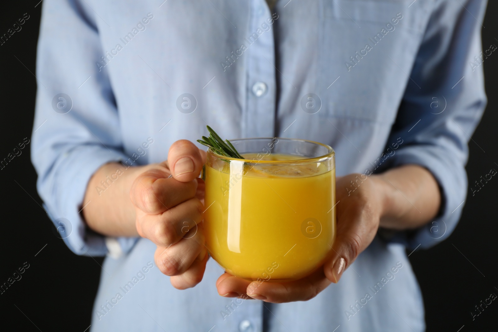 Photo of Woman holding cup of immunity boosting drink in hands, closeup