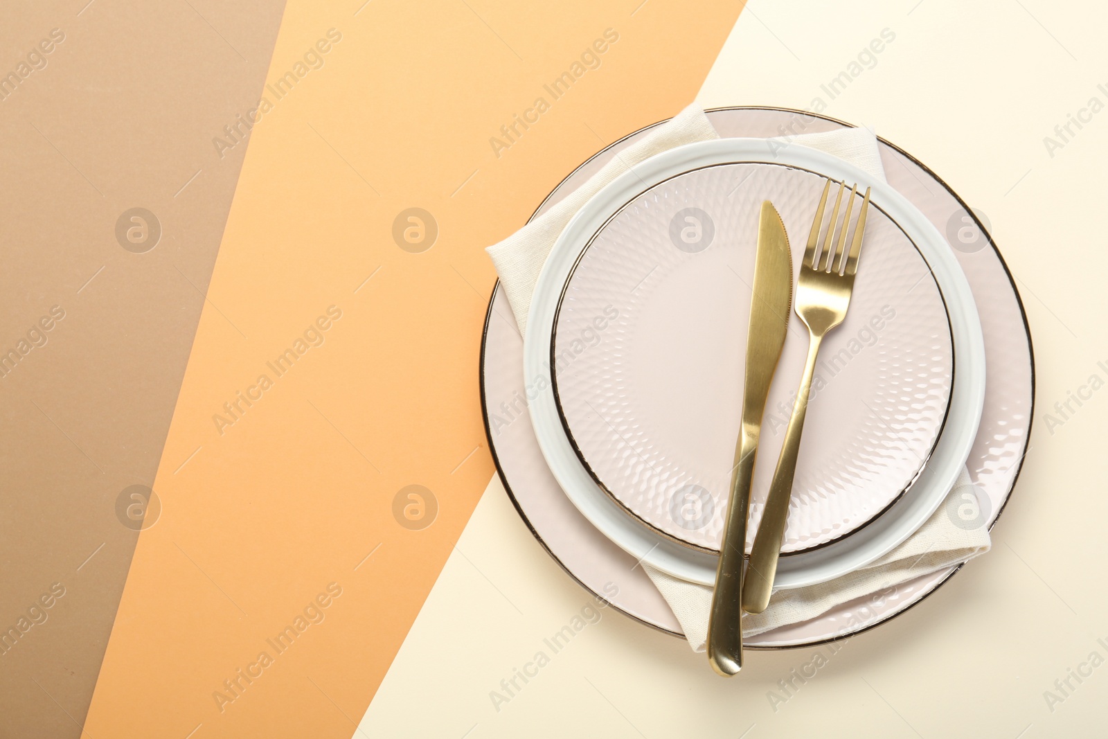 Photo of Ceramic plates, cutlery and napkin on color background, top view. Space for text