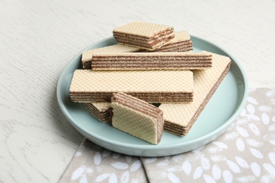 Photo of Plate of delicious crispy wafers with chocolate filling on white wooden table