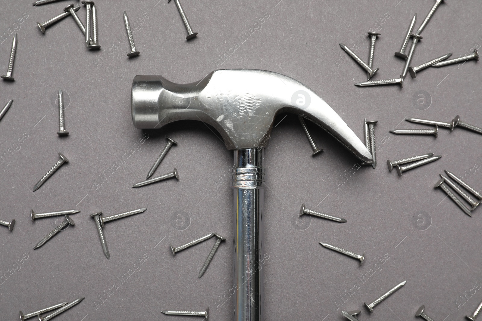 Photo of Hammer and metal nails on grey background, top view