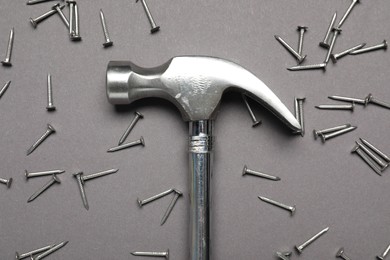 Hammer and metal nails on grey background, top view