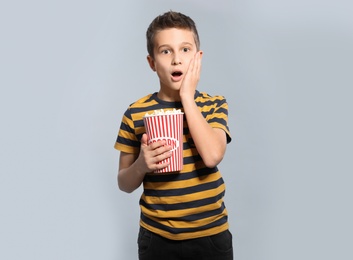 Photo of Emotional boy with popcorn during cinema show on grey background