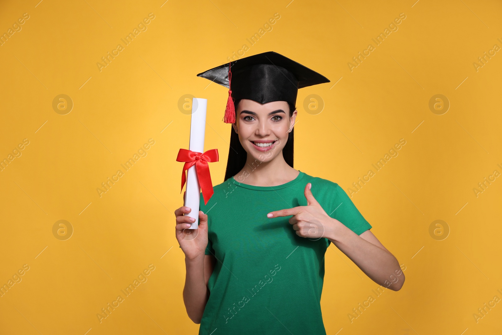 Photo of Happy student with graduation hat and diploma on yellow background