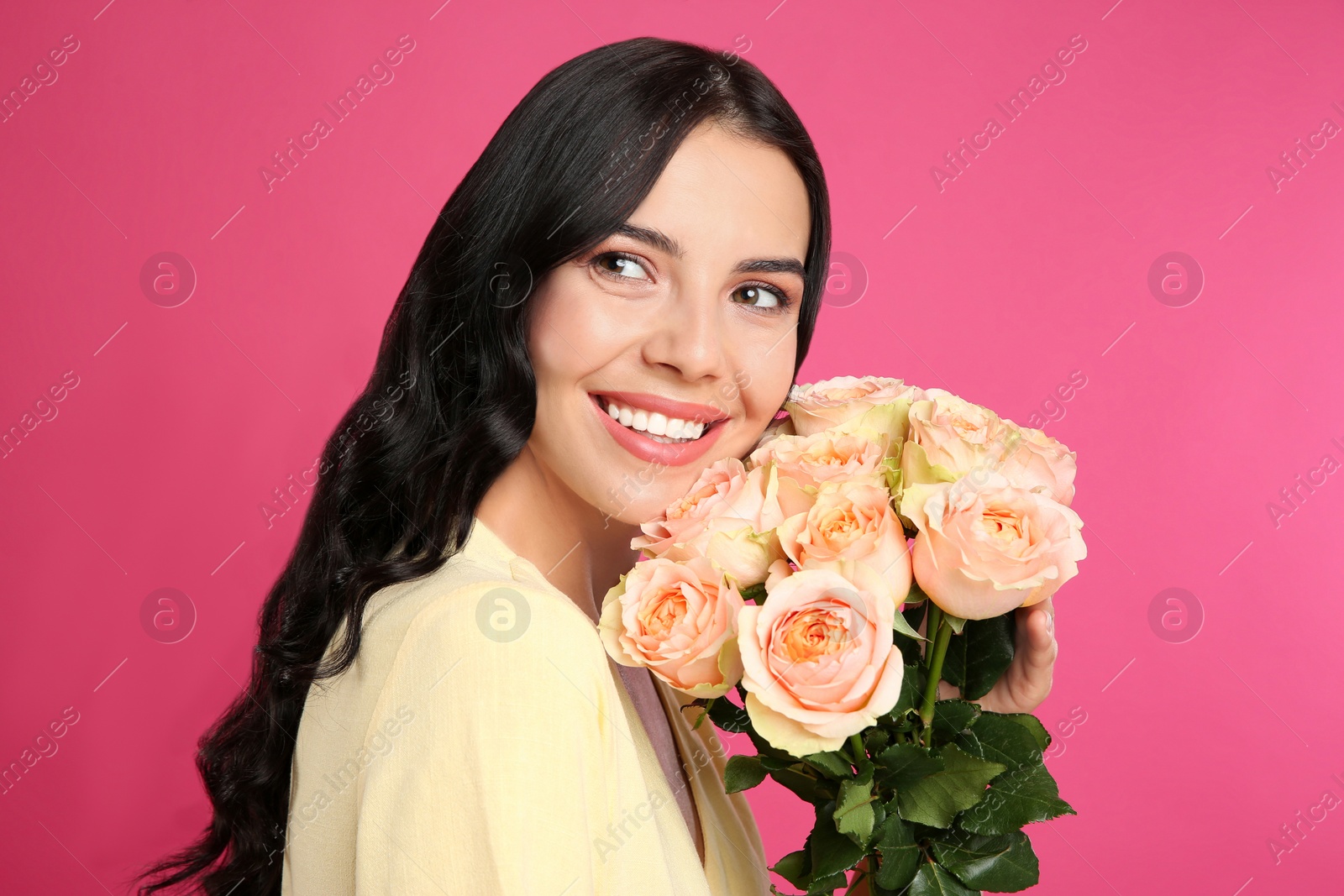 Photo of Portrait of smiling woman with beautiful bouquet on pink background