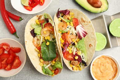 Delicious tacos with shrimps served on light grey table, flat lay