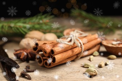 Different spices and fir tree branches on wooden table, closeup. Cinnamon, cloves, anise, cardamom, vanilla, nutmegs