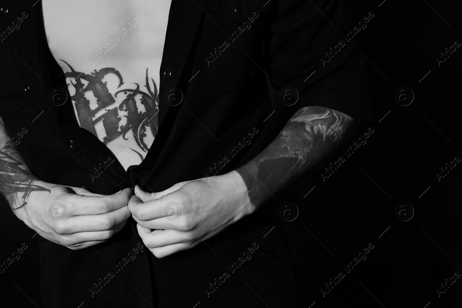 Image of Young man with tattoos on dark background, closeup. Black and white photography