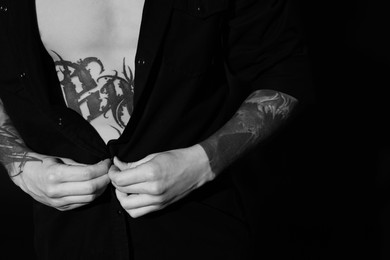 Young man with tattoos on dark background, closeup. Black and white photography