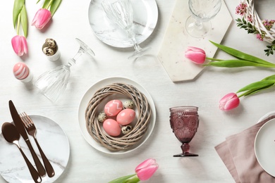 Festive Easter table setting with painted eggs on wooden background, top view