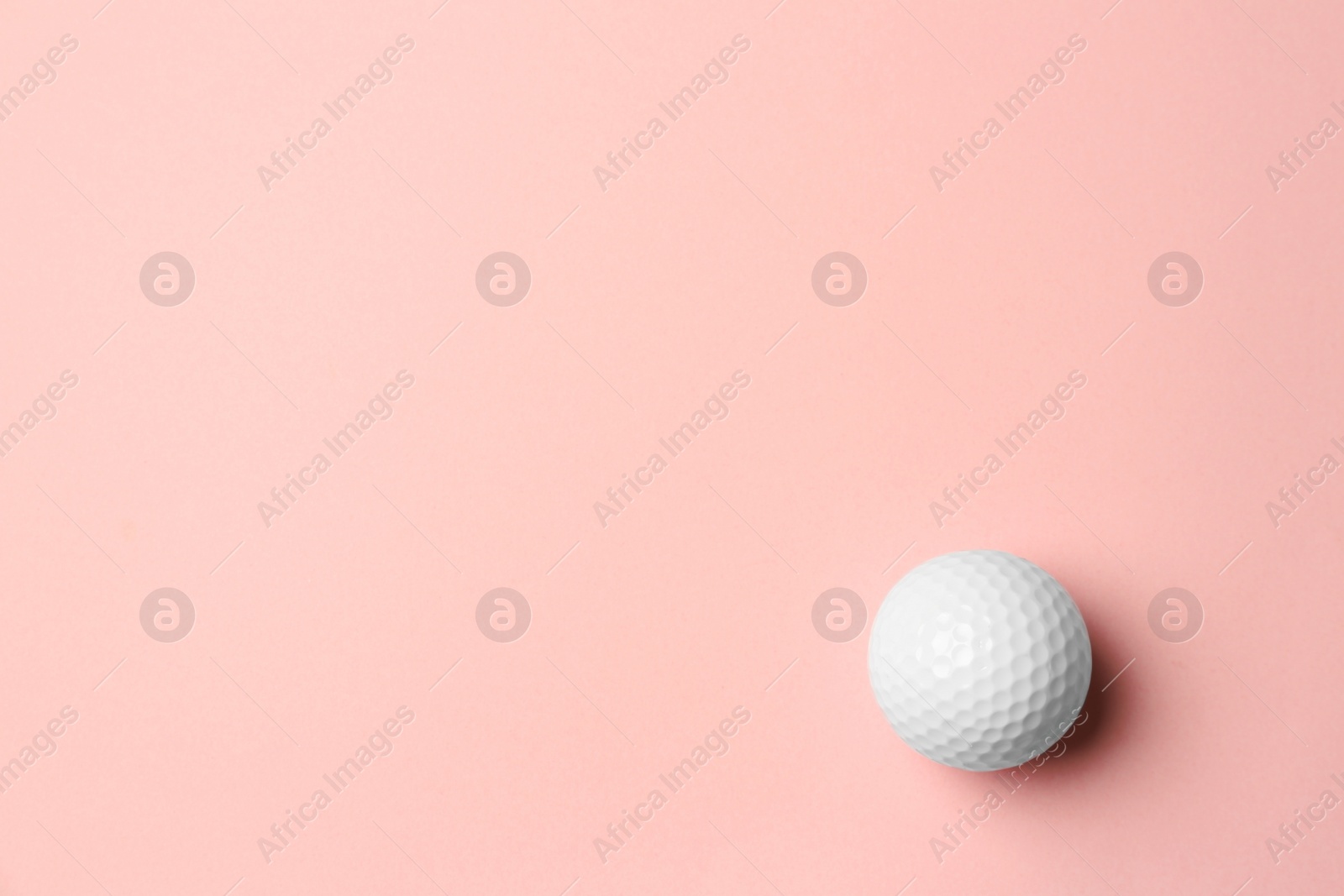 Photo of Golf ball on pink background, top view. Space for text