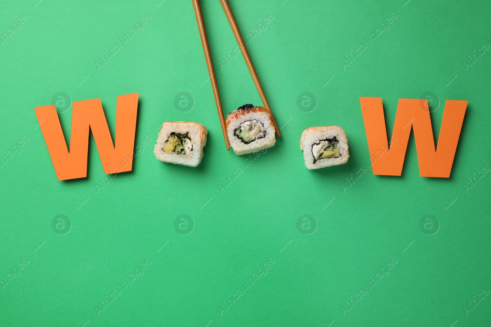 Photo of Word Wooow made with sushi rolls and paper letters on green background, flat lay