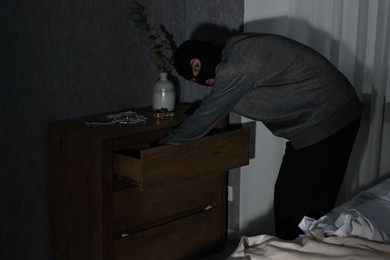 Photo of Thief stealing jewels in foreign house. Burglary