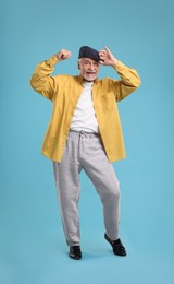 Photo of Happy senior man dancing on light blue background