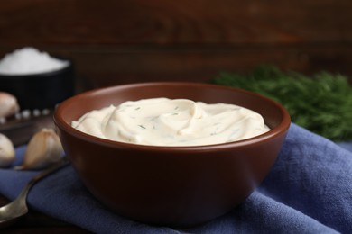 Photo of Tasty creamy dill sauce in bowl on blue kitchen towel, closeup