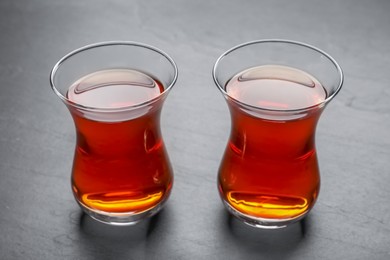 Photo of Glasses with traditional Turkish tea on black table, closeup