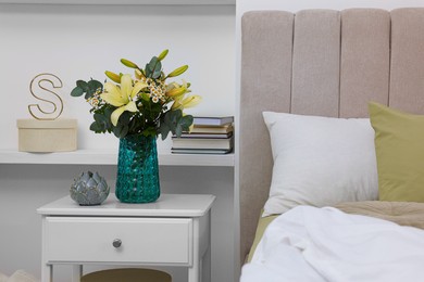 Photo of Bouquet of beautiful flowers and ceramic decor on nightstand in bedroom