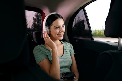 Photo of Young woman listening to music in modern taxi