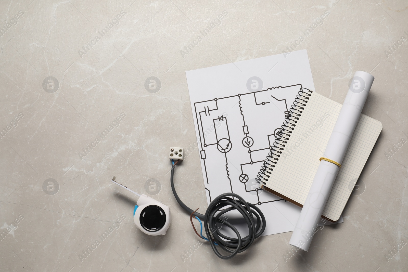 Photo of Wiring diagram, wires, tape measure and notepad on light table, flat lay. Space for text