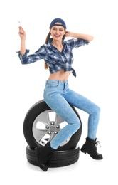 Young woman in seductive outfit with car tires on white background