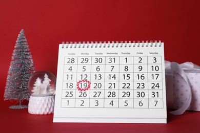 Photo of Saint Nicholas Day. Calendar with marked date December 19, gift box and festive decor on red background