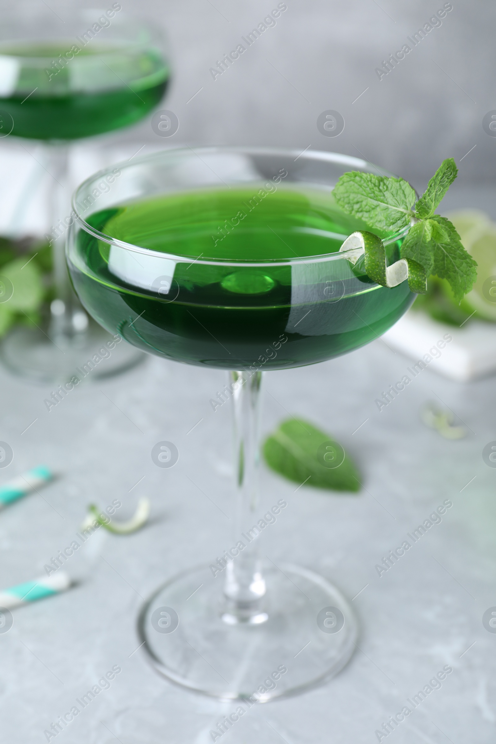 Photo of Delicious mint liqueur with green leaves on light grey marble table, closeup