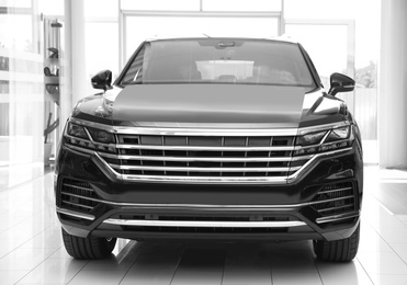 Photo of New luxury black car in modern auto dealership