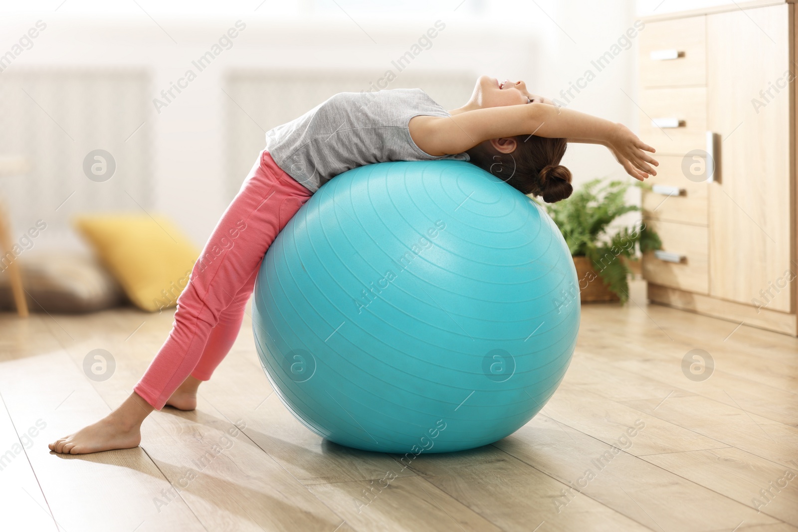 Photo of Little cute girl doing exercises with fitness ball at home