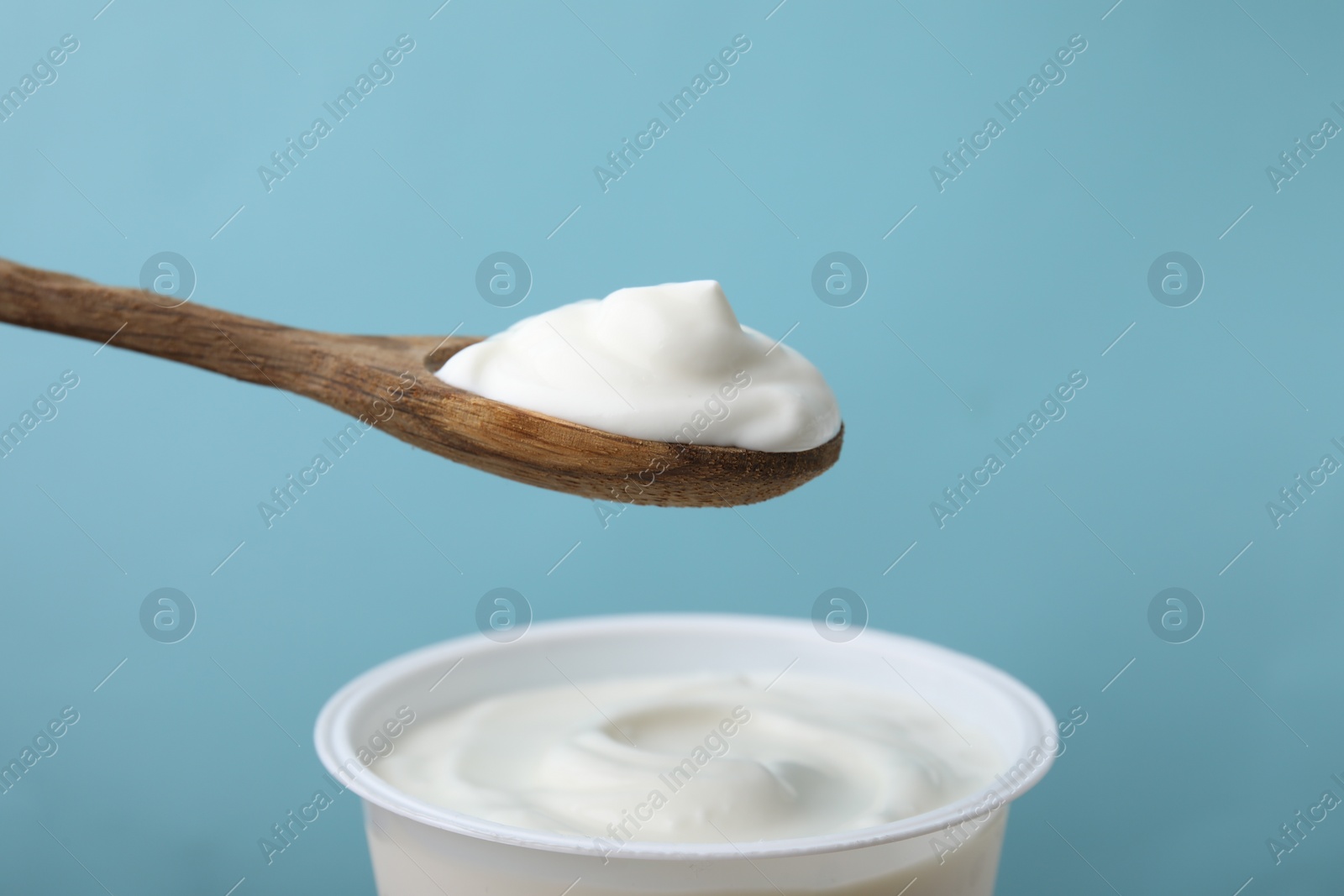 Photo of Eating delicious natural yogurt on light blue background