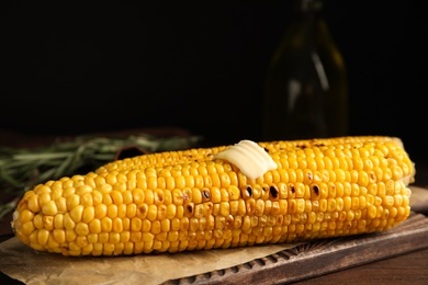 Fresh grilled corn cobs with butter on wooden table, closeup