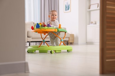 Photo of Cute little boy in baby walker at home
