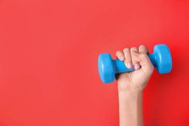 Photo of Woman holding vinyl dumbbell on color background, closeup with space for text