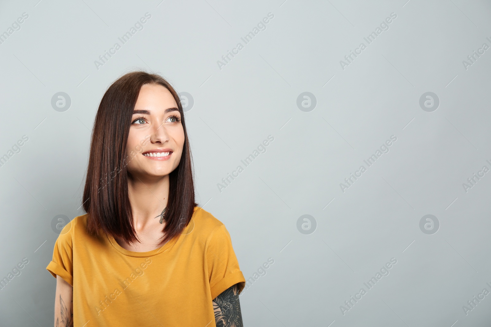 Photo of Portrait of pretty young woman with gorgeous chestnut hair and charming smile on light grey background, space for text